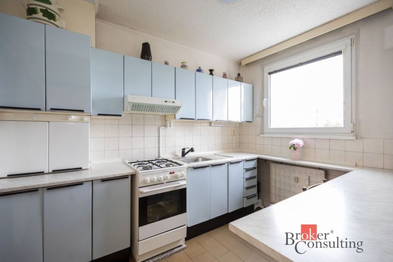 A kitchen in a 4-room apartment with light blue cabinets and a white tiled wall.