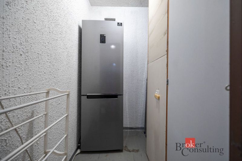 A combined refrigerator in a narrow room in a 4-room apartment with textured walls.