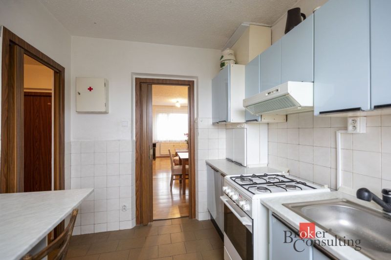 A kitchen in a 4-room apartment with a gas stove and blue cabinets.