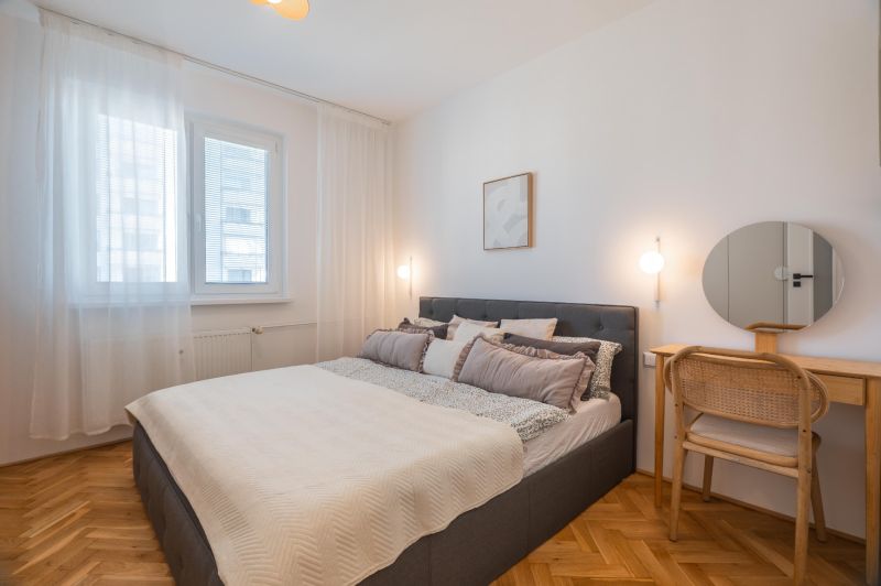 Bedroom in a 3-room apartment, with a bed, mirror, and wooden decor flooring.