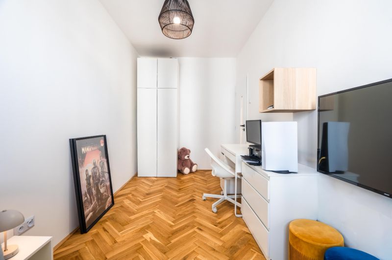 A study with a wooden decor floor in a 3-room apartment, white cabinets, and a TV.