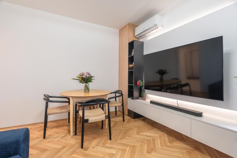 Dining area with a round table and chairs on a wooden-patterned floor.