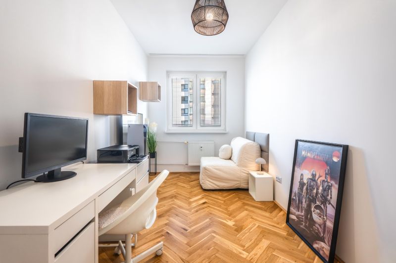 A workspace in a 3-room apartment with a wooden decor floor, a white table, and a sofa.