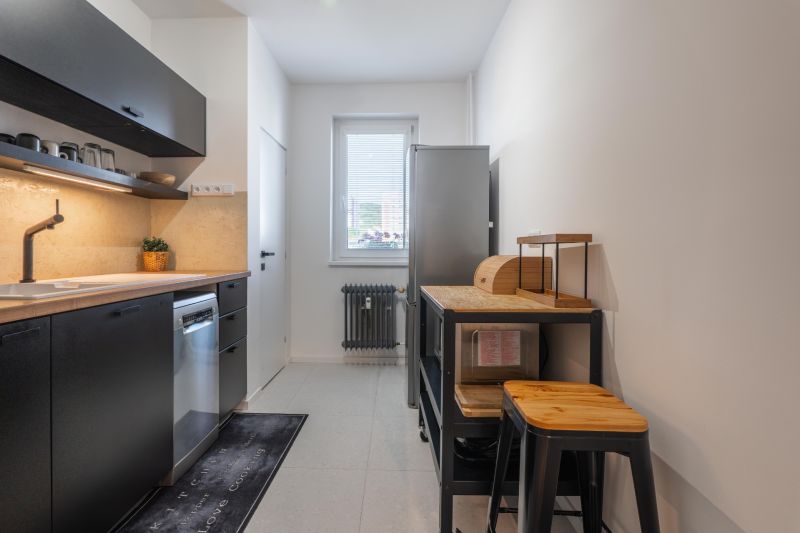 A kitchen with black cabinets, wooden details, and modern appliances in a three-room apartment.