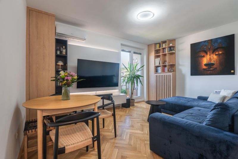Living room in a 3-room apartment with a wooden decor floor, a comfortable sofa, and a television.