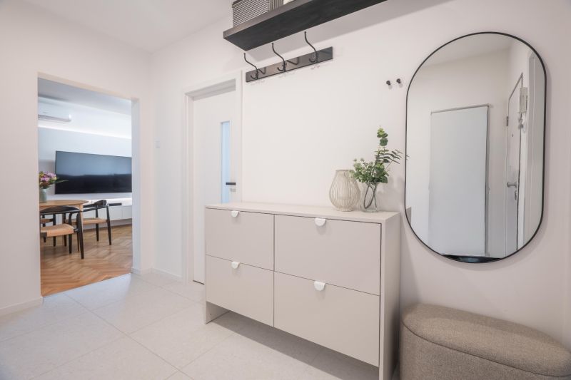 Entrance hall in a 3-room apartment with furniture, a mirror, and a view into the living room.