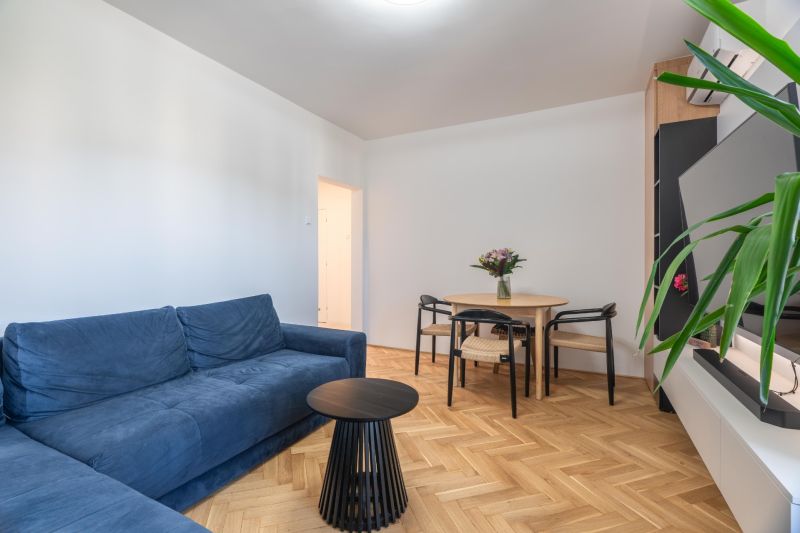 Living room with a blue sofa, table, and wooden decor flooring in a 3-room apartment.