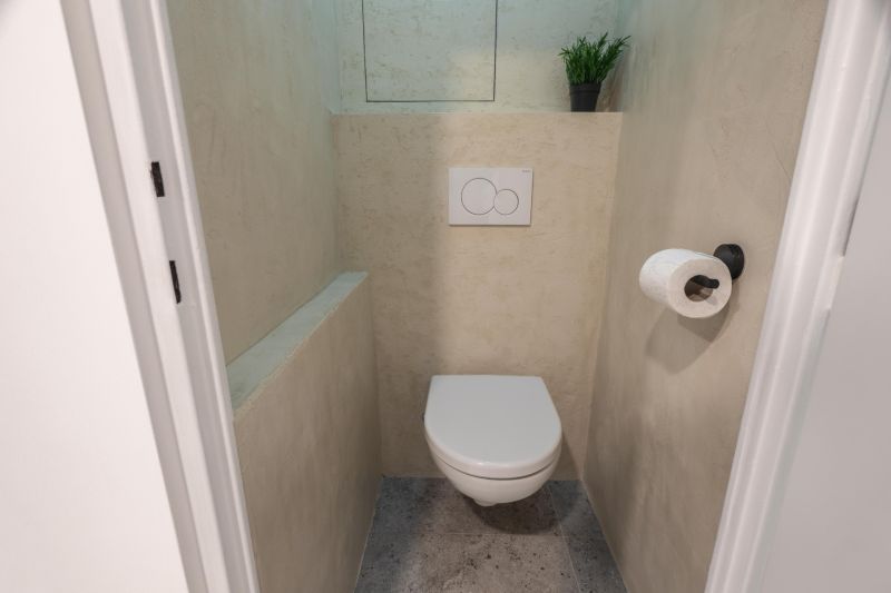 A toilet in a 3-room apartment with simple decoration and gray flooring.