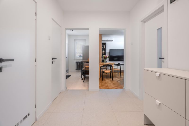 A hallway with white walls and entrances to the kitchen and living room in a three-room apartment.