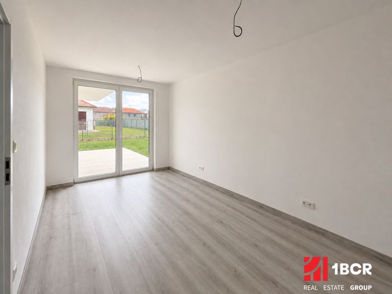 A spacious room with large windows and a wooden decor floor in a family house.
