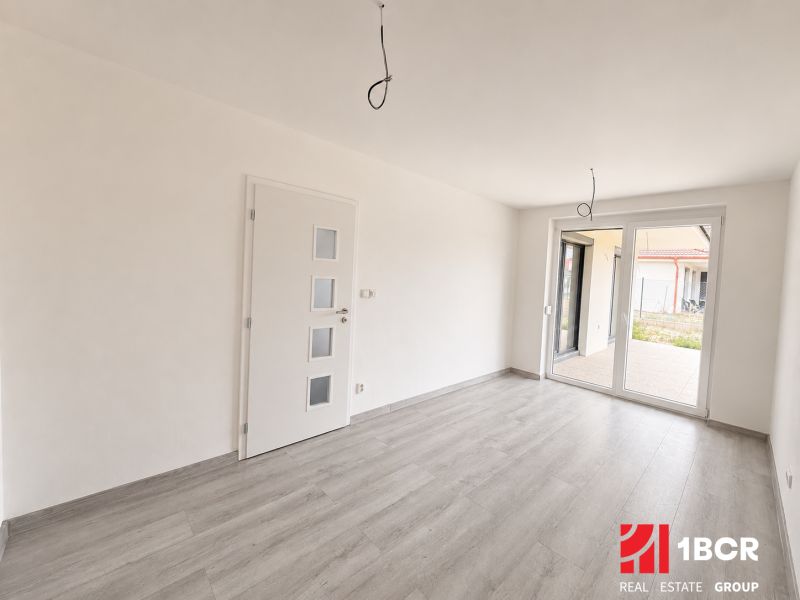 A bright room with wood-patterned flooring and large windows in a family house.