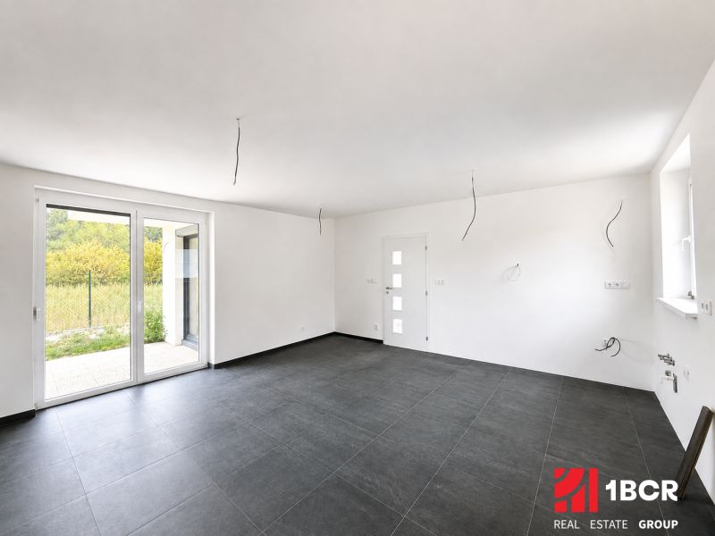 A spacious room with a large window and dark tiles in a family house.