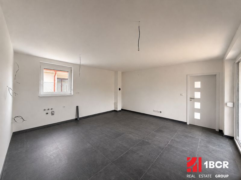 A bright room with dark ceramic tiles and a large window in a family house.
