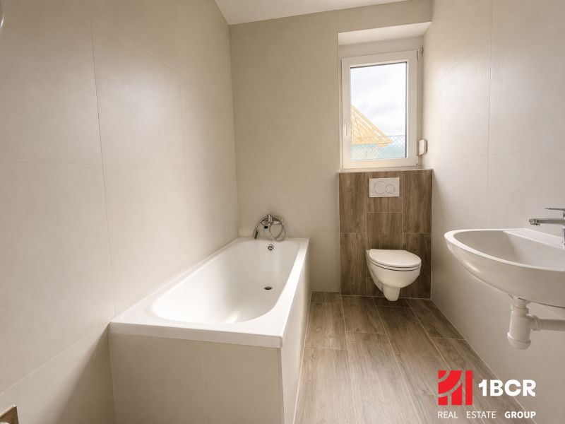 Bathroom with a bathtub, toilet, and sink, floor with wooden decor, family house.
