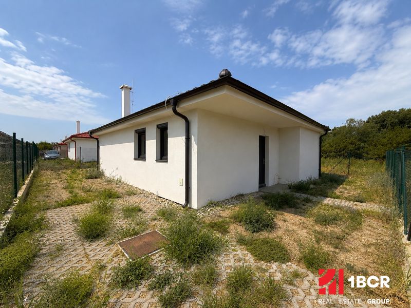 A family house in Most pri Bratislave, white exterior, fenced yard, partially grassed plot.