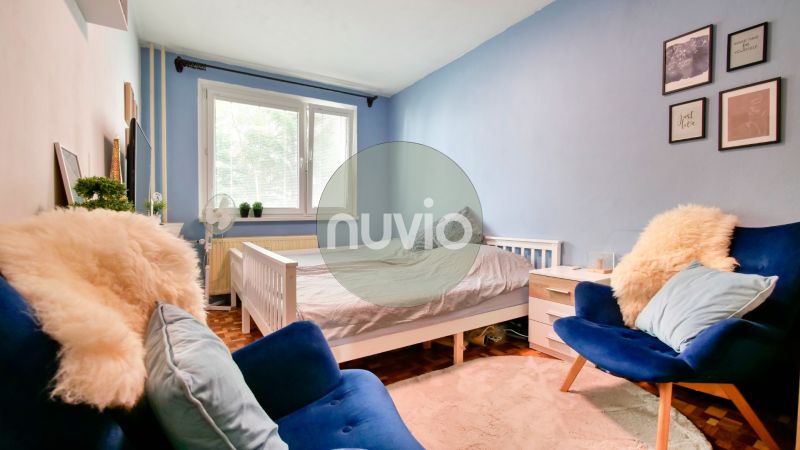 A bedroom in a two-room apartment with blue walls, white furniture, and armchairs.