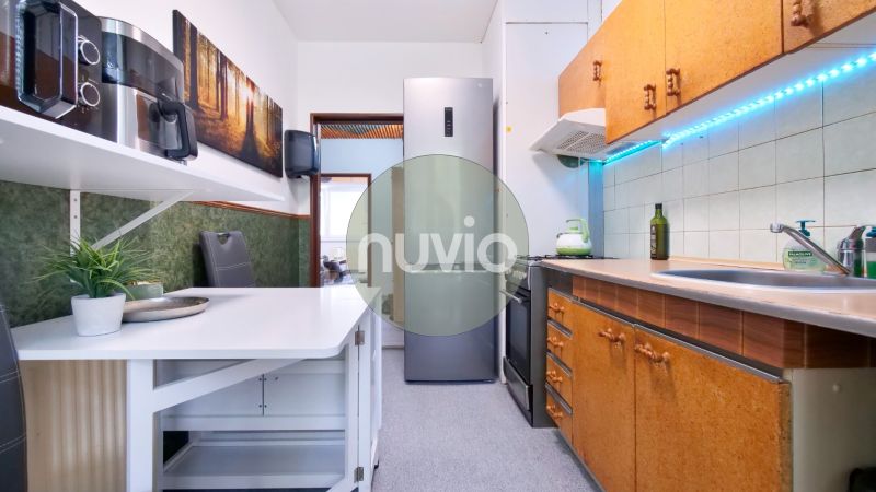 A kitchen of a 2-room apartment with a wooden decor, a kitchen sink, and an appliance.