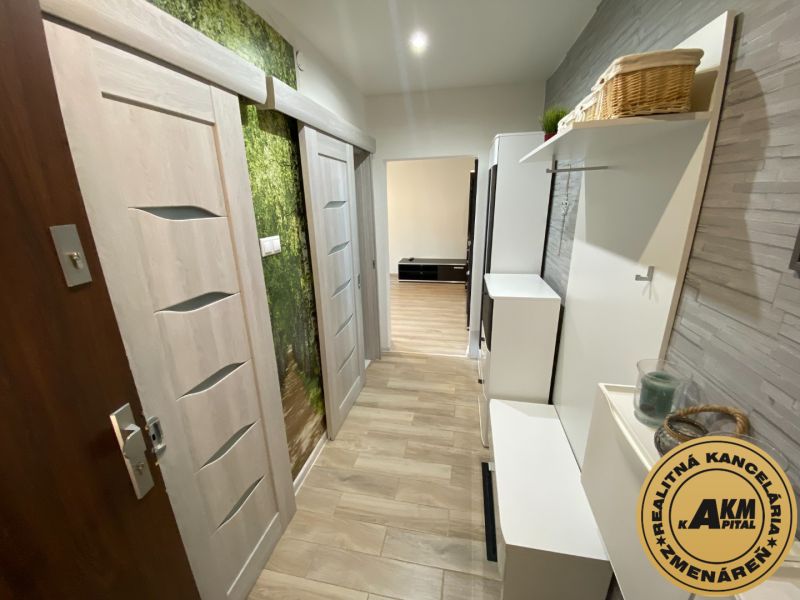 The hallway of a 2-room apartment with a wooden decor floor and stone wall cladding.