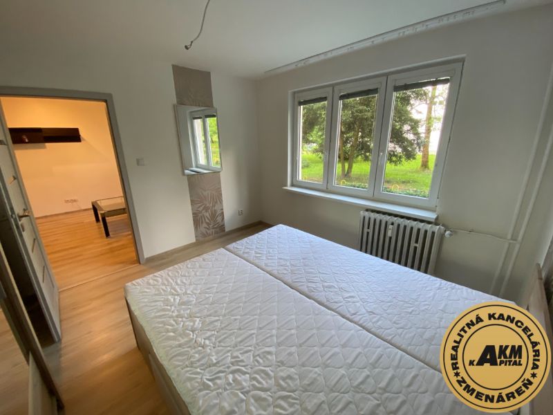 A bright bedroom in a 2-room apartment with a window and a wooden decor floor.