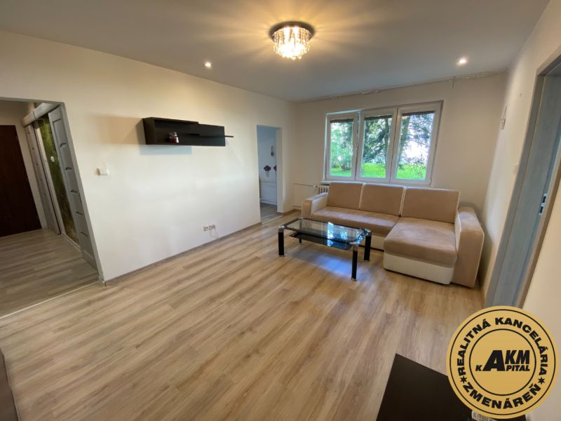 Living room in a two-room apartment with a wooden decor floor and a light sofa.