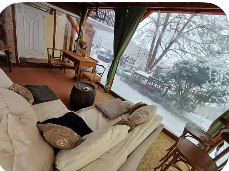 Winter garden with a sofa, table, and chairs in a family house.