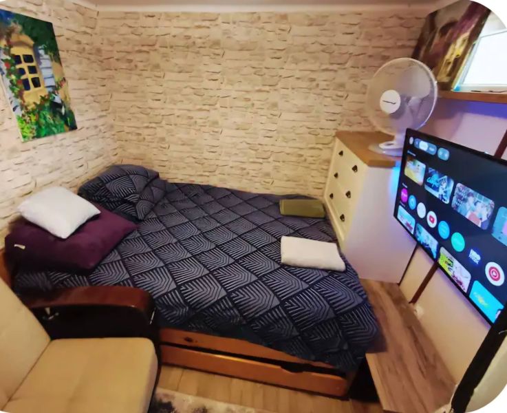 A bedroom in a family house with a bed, a television, and a floor with a wood decor.