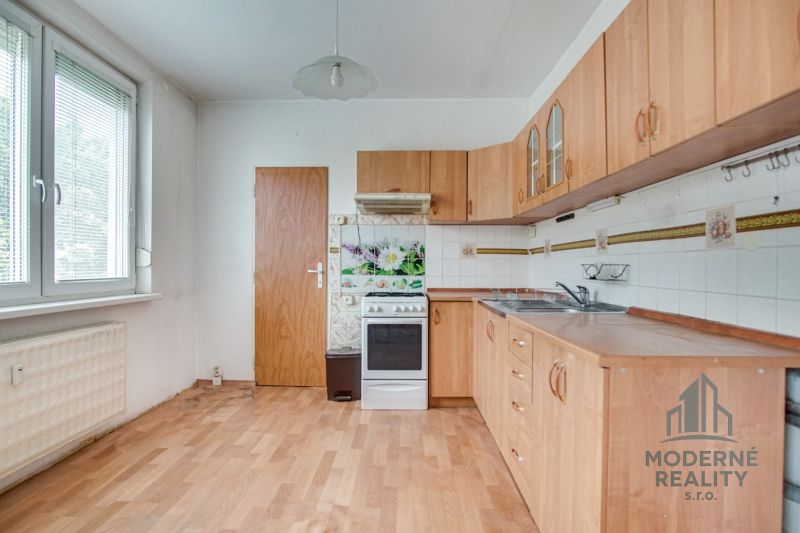 A kitchen in a 3-room apartment with a wooden decor floor and a white gas stove.