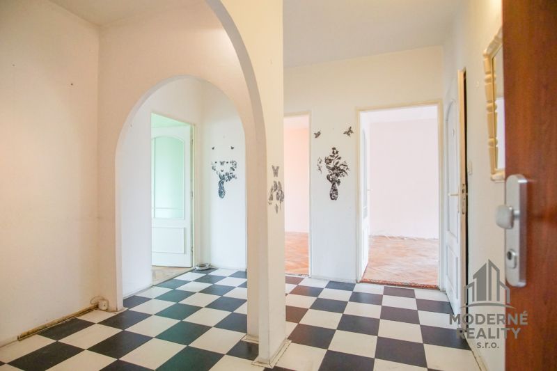 An interior with checkerboard tiles, an arch, and a floor with a wooden decor in a 3-room apartment.