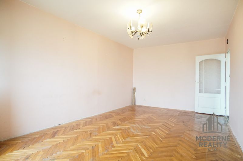 Interior of a 3-room apartment with a wooden decor floor and a chandelier on the ceiling.