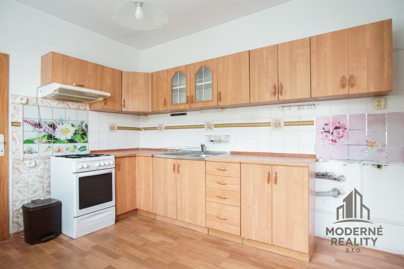 A kitchen in a 3-room apartment with a wooden decor floor and light furniture.