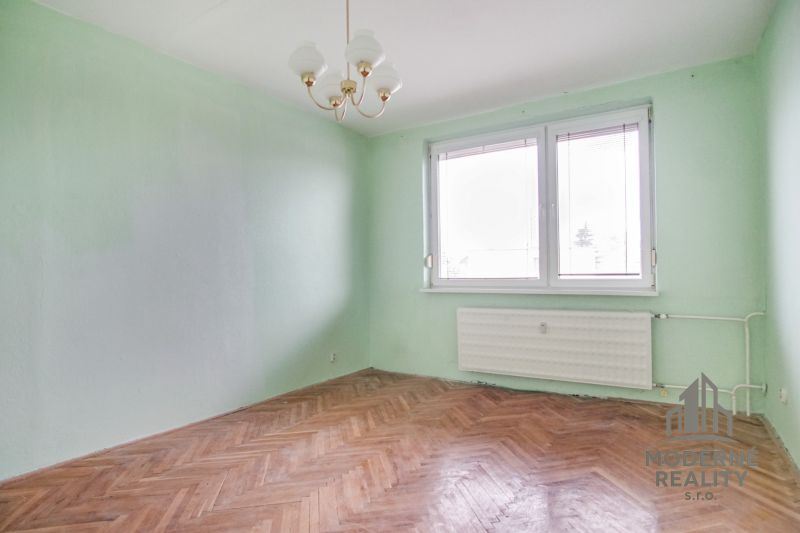 A room in a 3-room apartment with a wood-patterned floor and green walls.