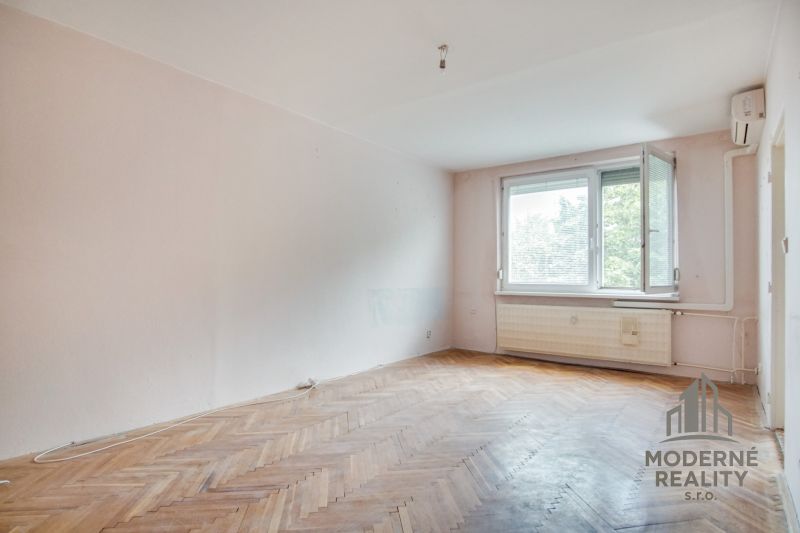A room in a 3-room apartment with a wooden decor floor and white walls.