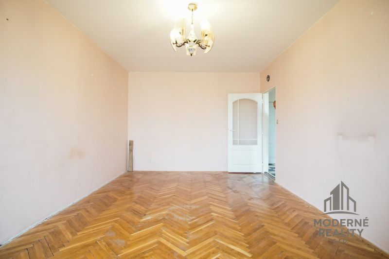 An empty room with a wooden decor floor in a 3-room apartment.