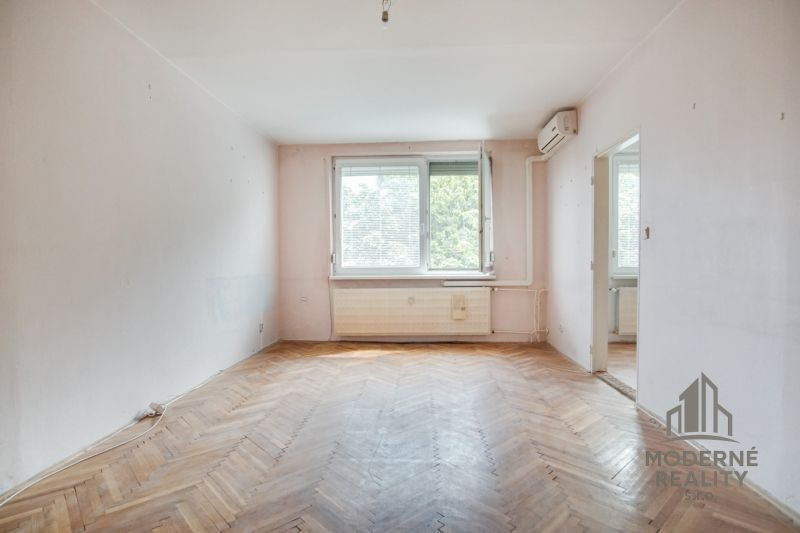 Living room in a three-room apartment with a wooden decor floor and a large window.