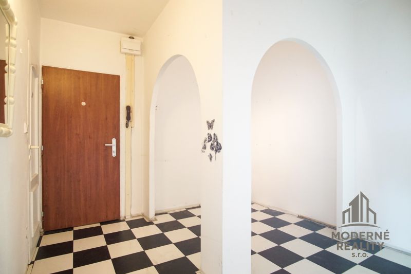 Entrance hall in a 3-room apartment with black and white tiles and wooden doors.