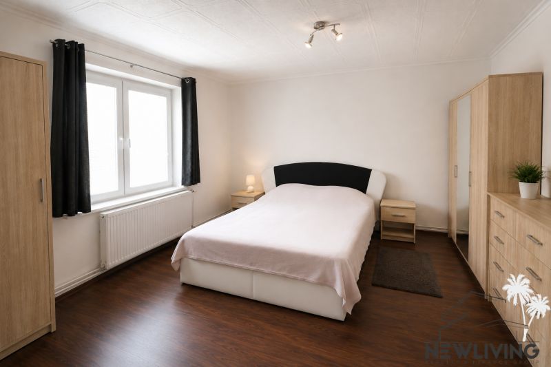 A bedroom in a family house with a wood-patterned floor, light, and furniture in neutral colors.