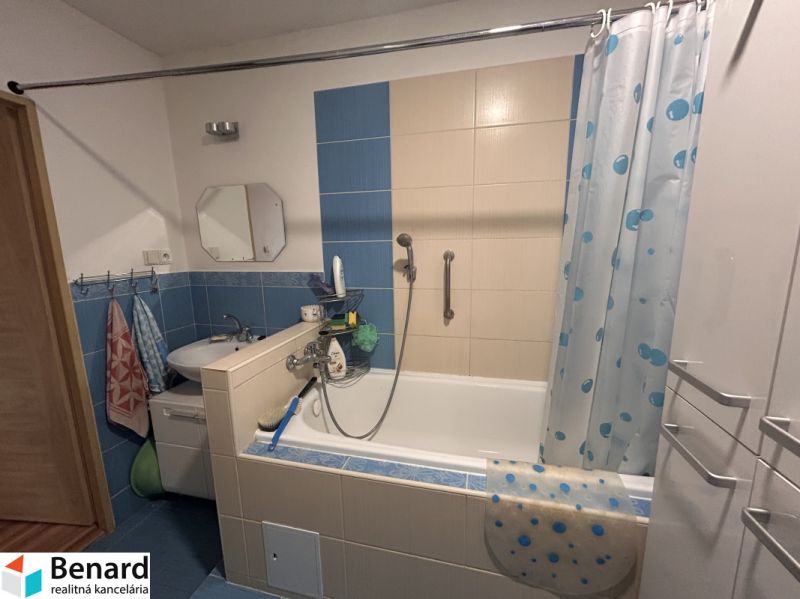 A bathroom with a bathtub and blue tiles in a three-room apartment.