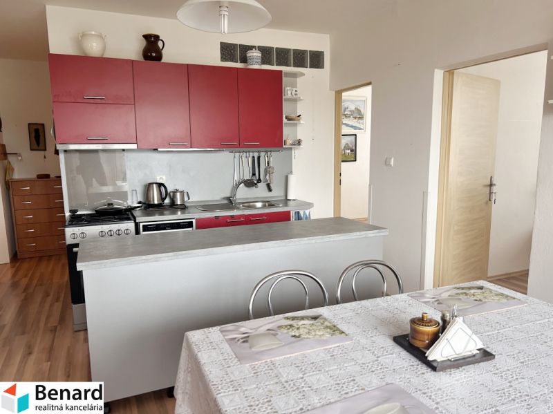 A kitchen with a table, cabinets, and a floor with a wood decor in a 3-room apartment.
