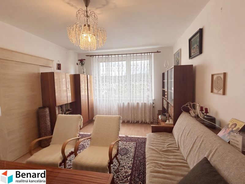 Living room in a three-room apartment with a wooden decor floor and a large window.