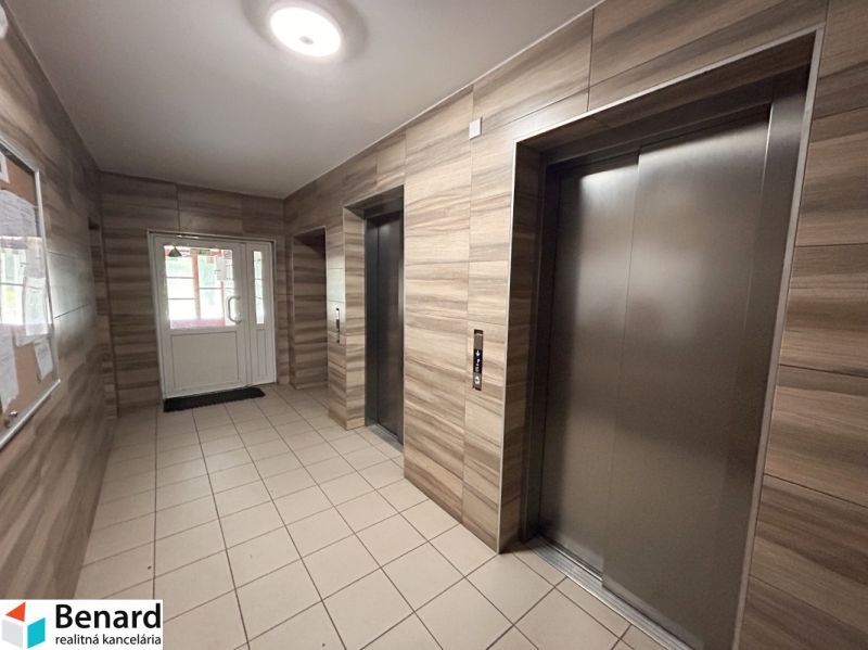 The entrance hall with elevators, wooden decor and tiles, typical for a 3-room apartment.