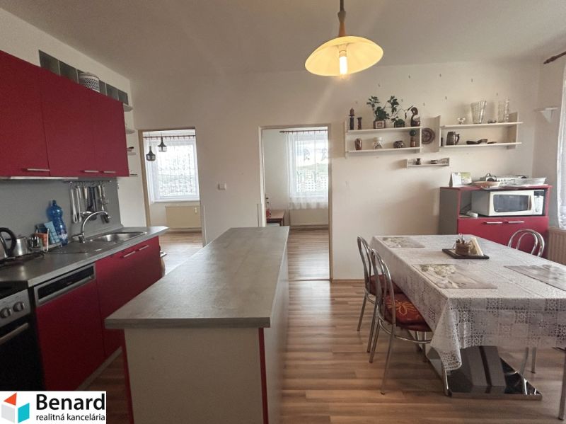 A kitchen in a 3-room apartment with red cabinets and a wooden decor floor.