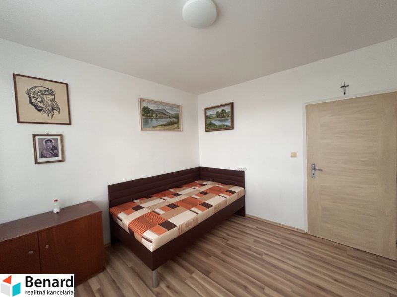 Bedroom in a 3-room apartment with a bed, wood-patterned flooring, and artworks on the walls.