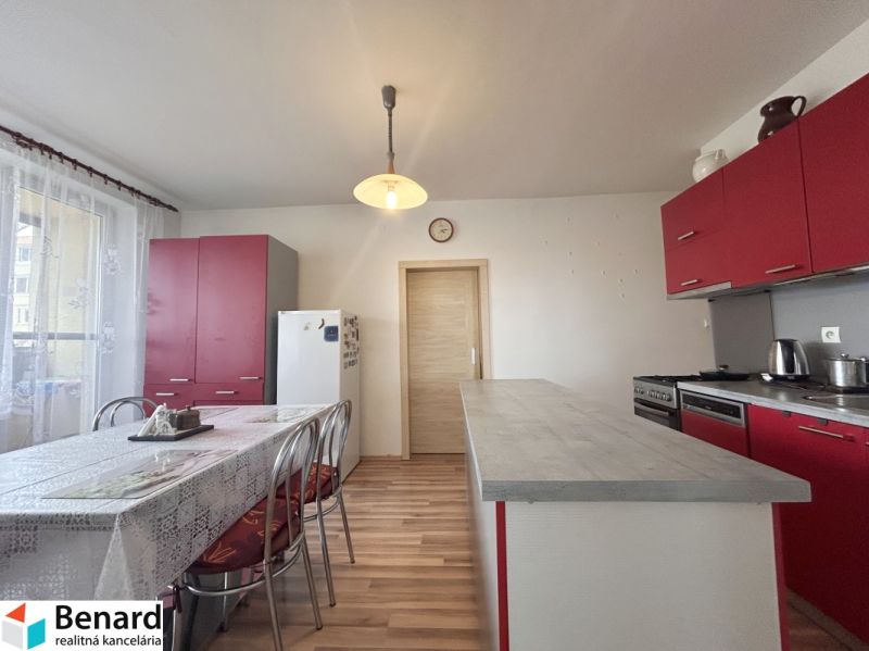 A kitchen in a 3-room apartment with red cabinets and a wood-patterned floor.