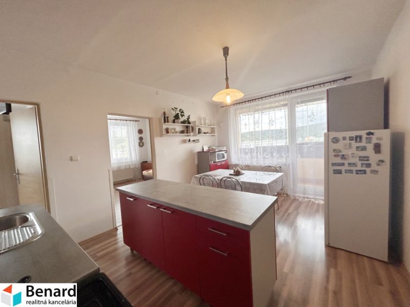 A kitchen with a dining area in a three-room apartment with a wooden decor floor.