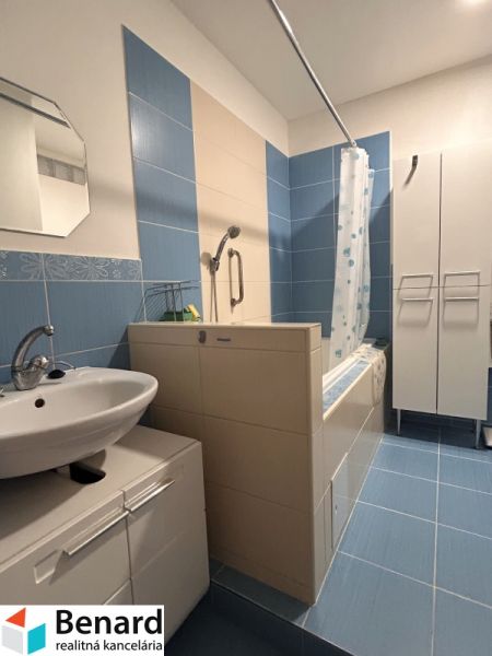 A bathroom with blue tiles and a bathtub in a 3-room apartment.