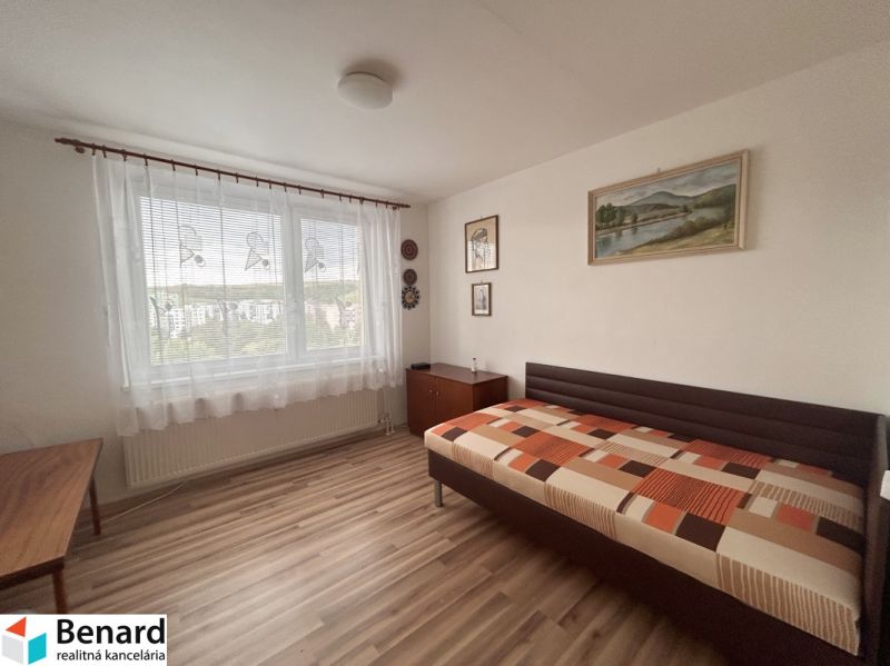 A room with a bed, paintings, and a floor with a wooden decor in a 3-room apartment.