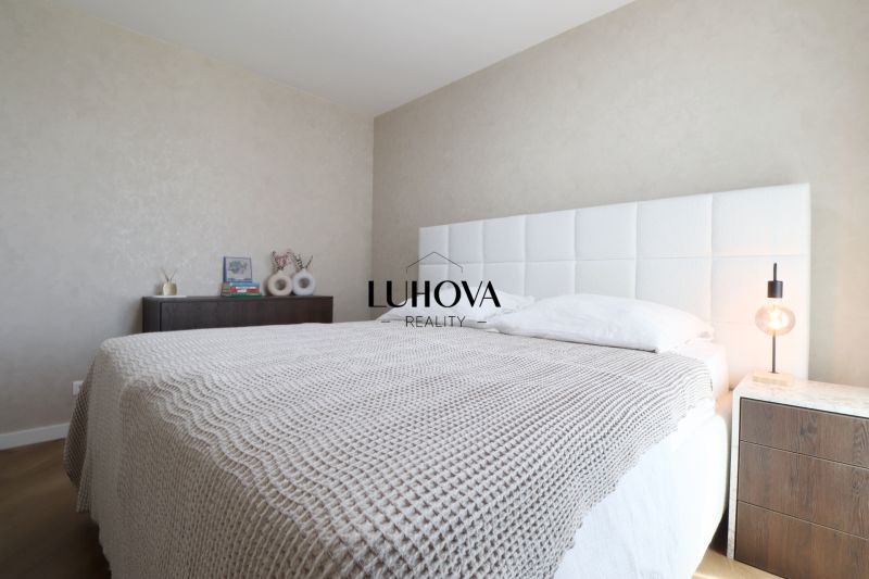 A bedroom in a 3-room apartment with a white bed and a nightstand.