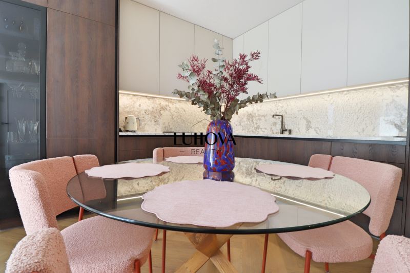 Dining area with a round table and pink chairs in a 3-room apartment.