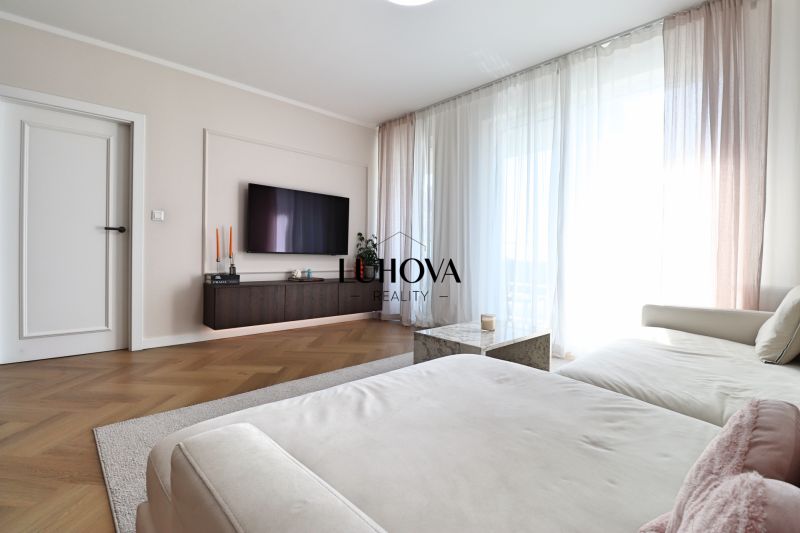 Living room in a 3-room apartment with a sofa, TV, and wooden decor flooring.