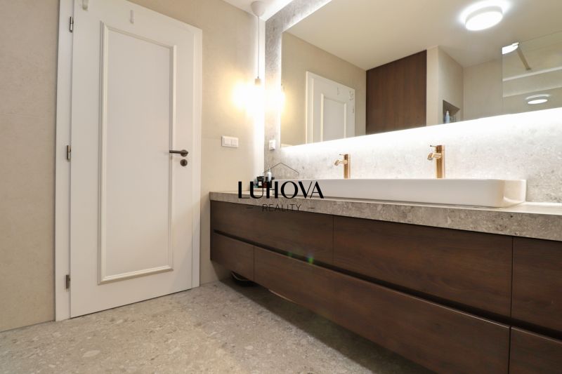 A bathroom with a large mirror and a hanging cabinet with a wooden decor in a 3-room apartment.